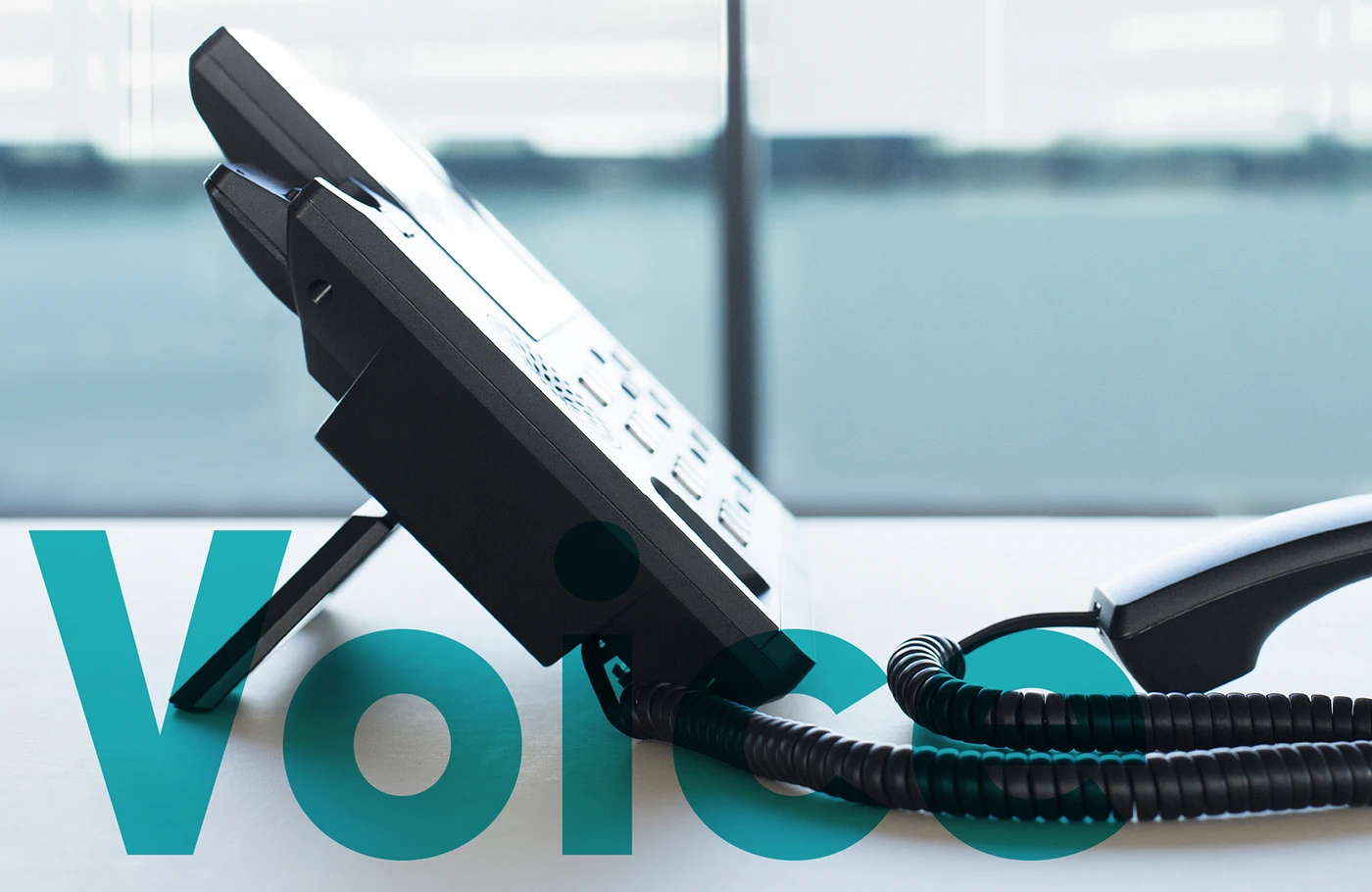 Ein Telefon steht am Tisch, der Hörer liegt davor. Schriftzug Voice als Overlay.